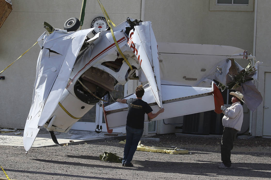 Workers guide a single-engine plane to the ground after it crashed into the terminal building s ...