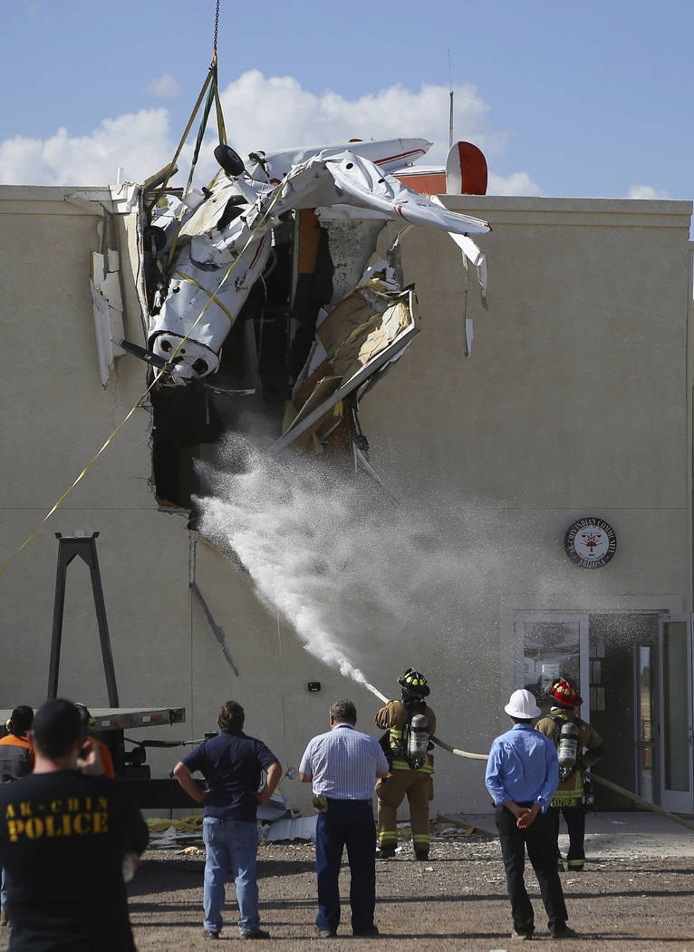 Fire personnel hose down the crash site as workers remove a single-engine plane after it crashe ...