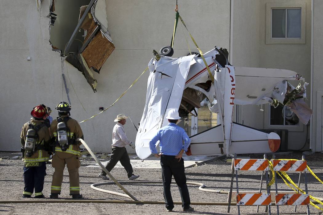 Workers remove a single-engine plane after it crashed into the terminal building shortly after ...