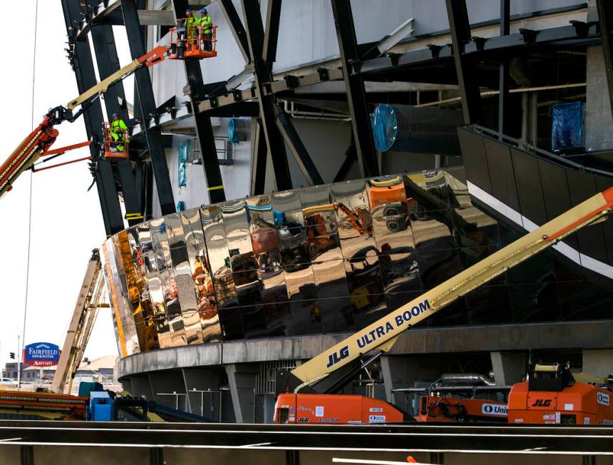 Crews work to install glass panes along the lower lever of Allegiant Stadium on Tuesday, Sept. ...