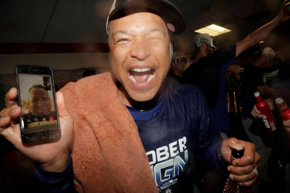 Los Angeles Dodgers manager Dave Roberts holds a cell phone during a video conference with inju ...