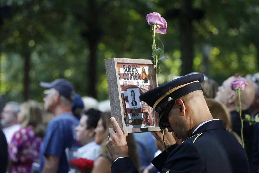 A man holds a photo of a victim during a ceremony marking the 18th anniversary of the attacks o ...