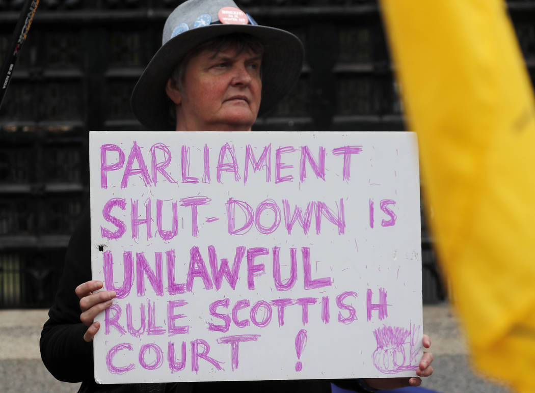 A Pro EU protestor shows a poster in front of the Houses of Parliament entrance in London, Wedn ...