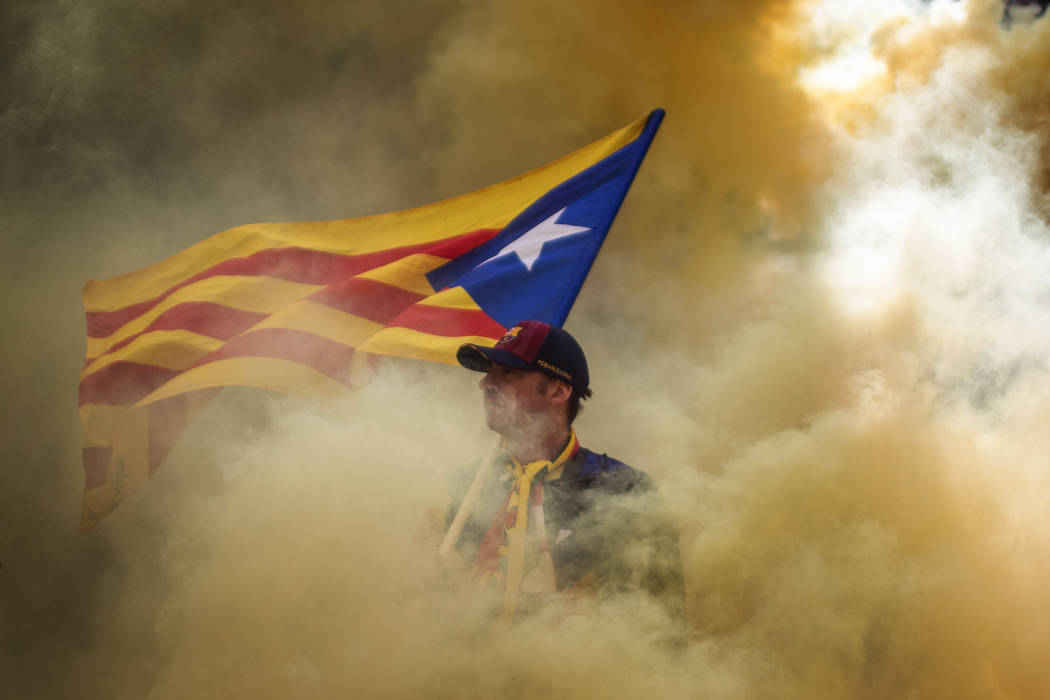 A man holding an independence flag is seen through the smoke thrown by demonstrators during the ...