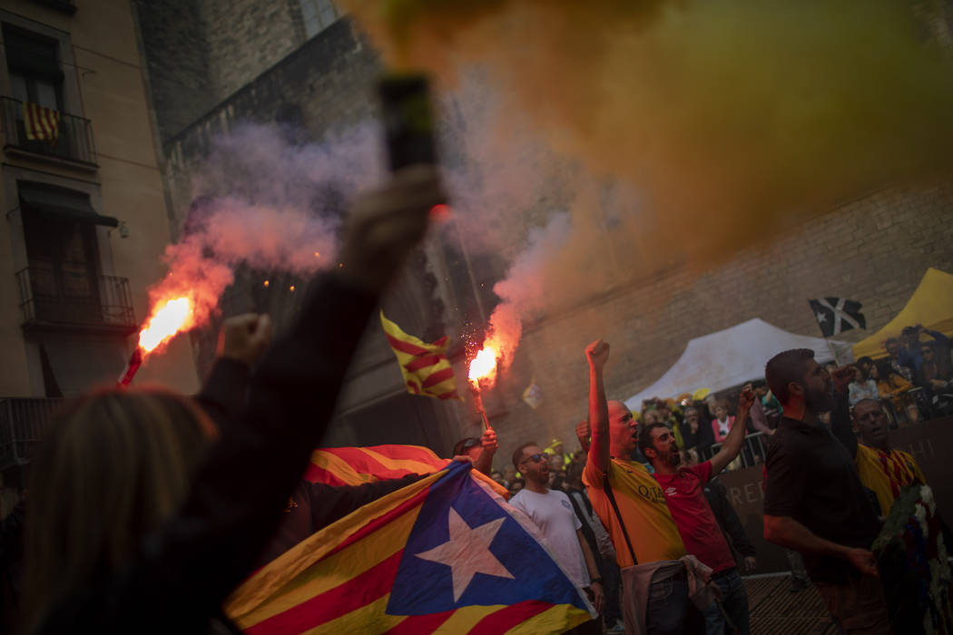 Protesters hold independence flags and flares during the Catalan National Day in Barcelona, Spa ...