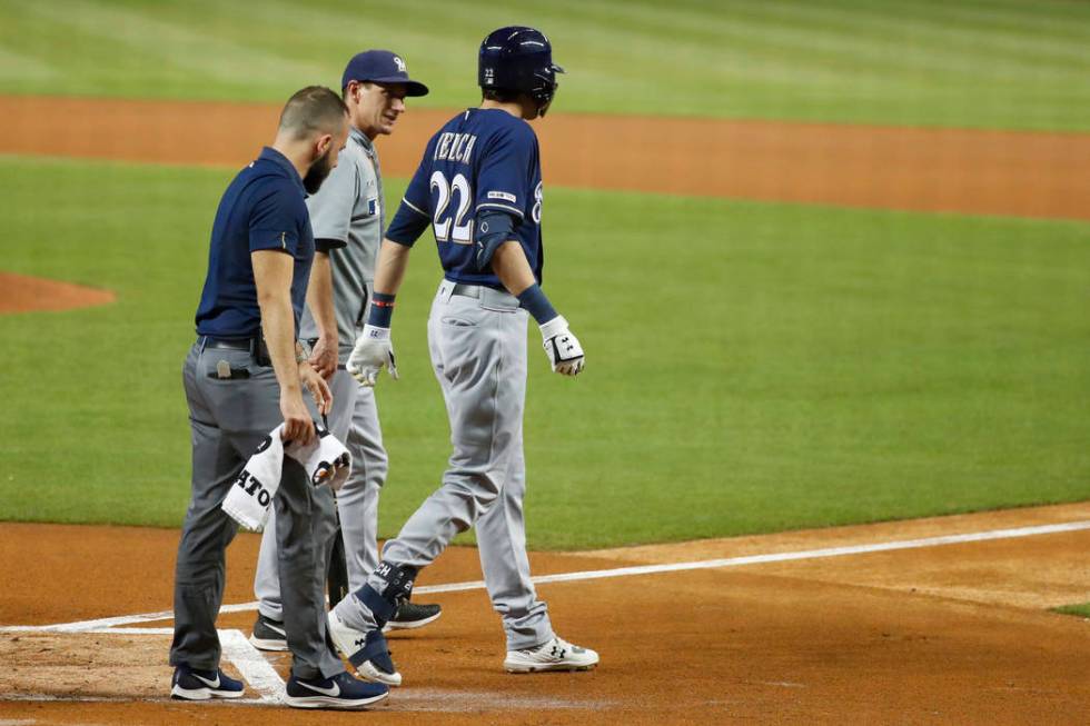 Milwaukee Brewers' Christian Yelich (22) walks off the field with a trainer and manager Craig C ...