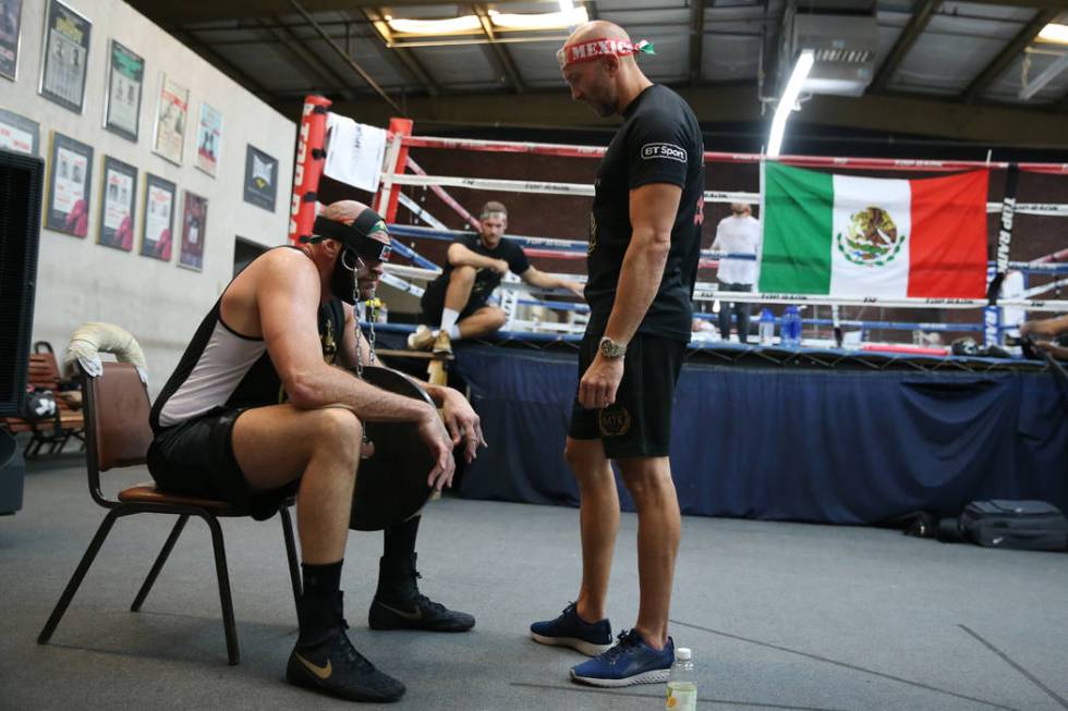 Tyson Fury, left, with his trainer Kristian Blacklock, works his neck by lifting weights with h ...