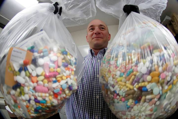 Narcotics detective Ben Hill, with the Barberton Police Department, shows two bags of medicatio ...