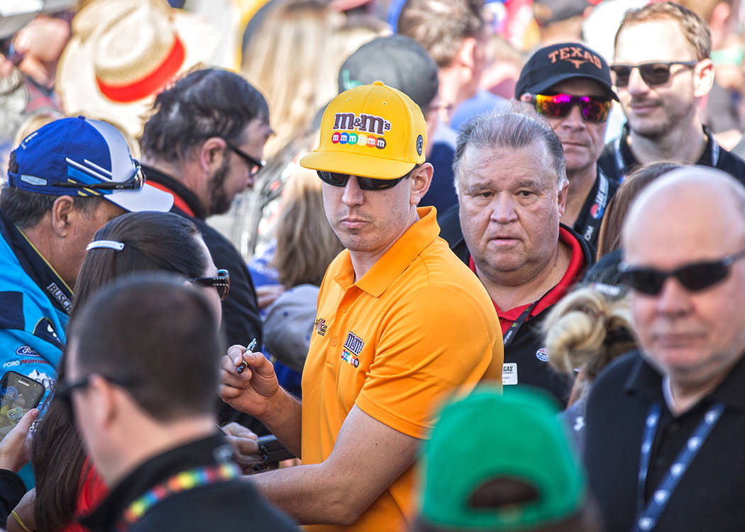 Kyle Busch, middle, signs autographs before the start of the Monster Energy NASCAR Cup Series P ...