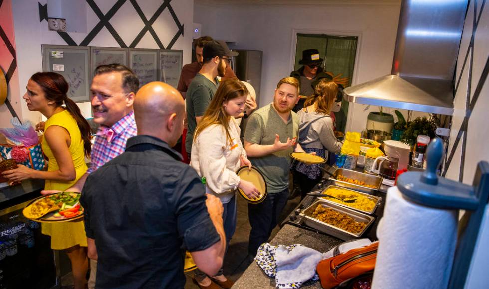 Guests gather in the kitchen for a buffet-style dinner during the Oakey Family Supper Club even ...