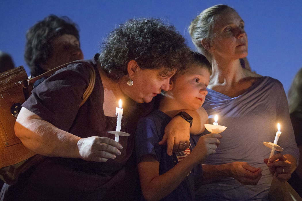 Paula Davis' brother Nathan Davis, center, holds a candle with his aunt Brenda Miraglia, left, ...