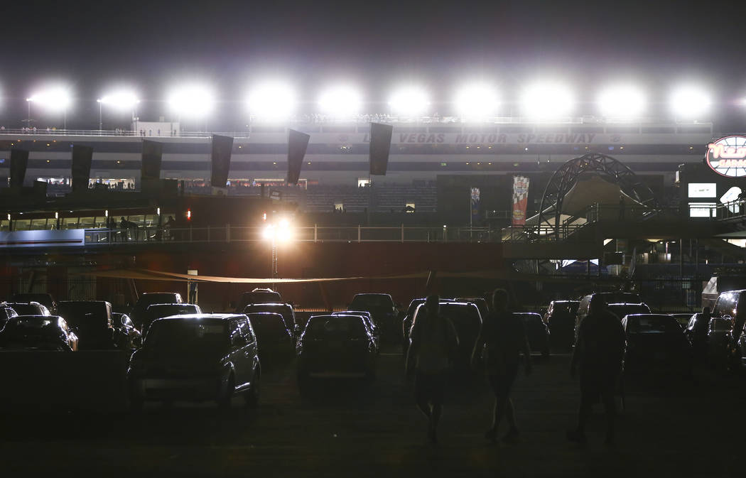 Attendees walk through a parking lot as drivers compete during the NASCAR World of Westgate 200 ...