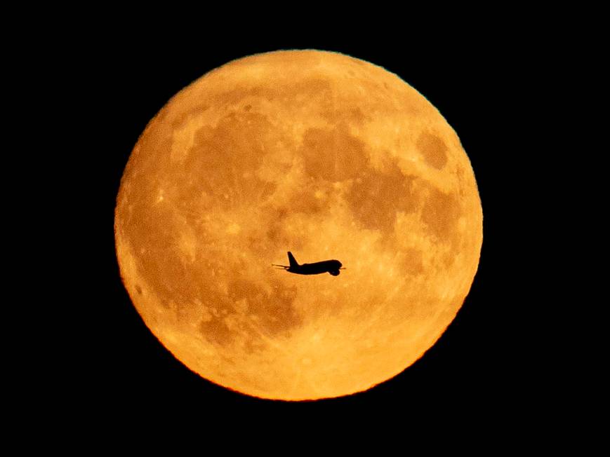 An aircraft passes the full moon as it approaches the airport in Frankfurt, Germany, Friday, Se ...