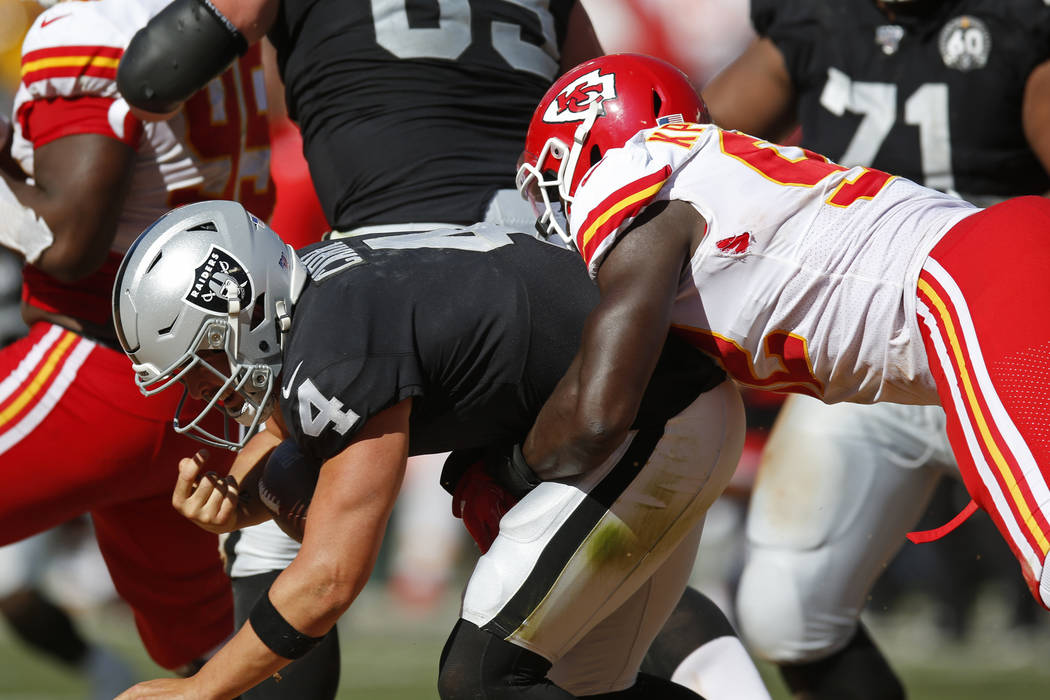 Oakland Raiders quarterback Derek Carr is brought down by Kansas City Chiefs defensive end Tano ...