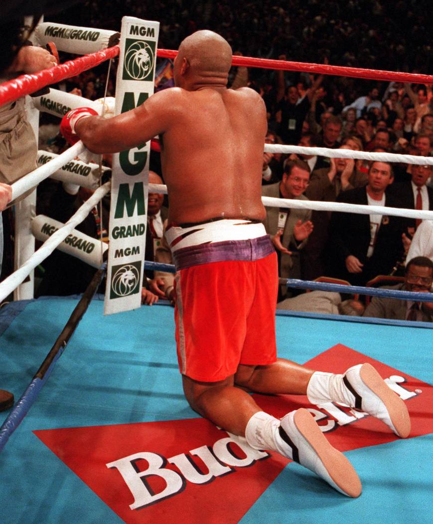 George Foreman kneels and prays after knocking out Michael Moorer in the 10th round for world h ...