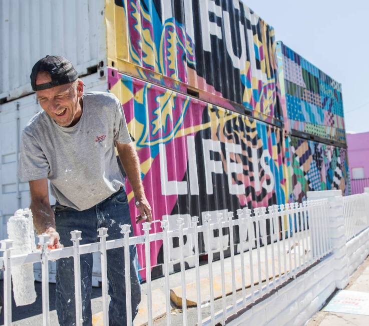 Jonathan Strublein paints a fence in preparation for Life is Beautiful music festival in downto ...