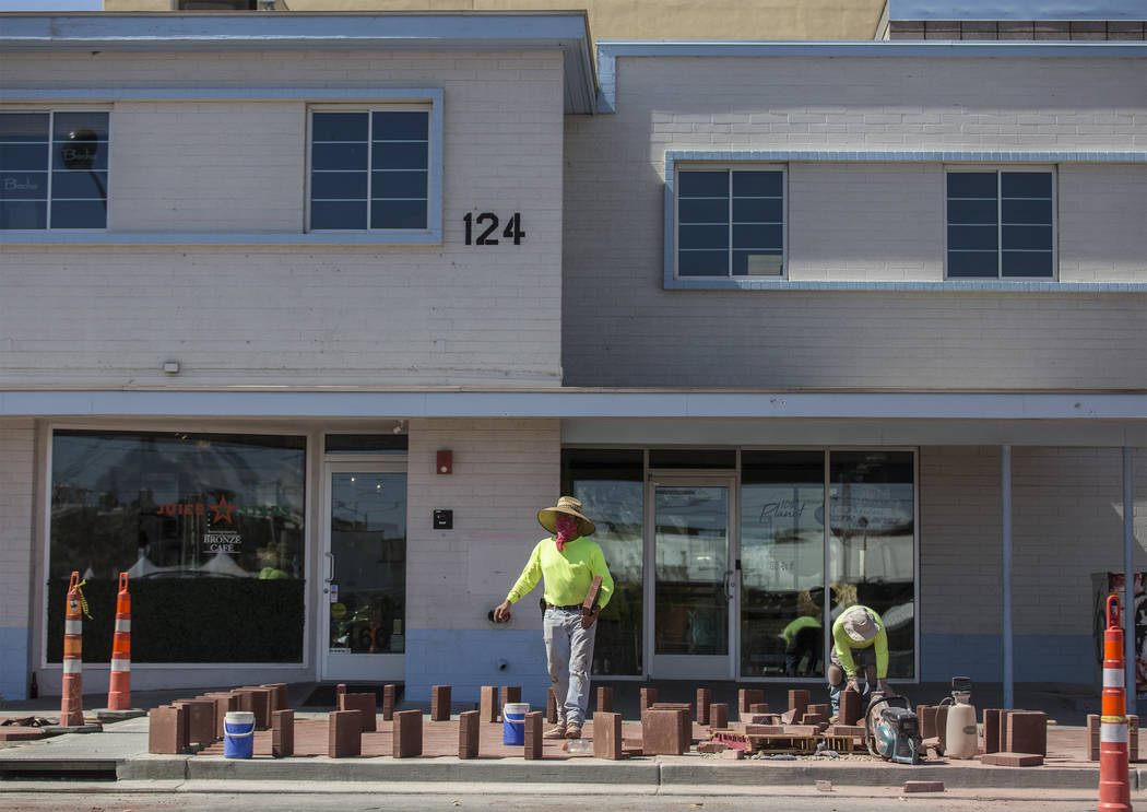 Construction workers lay brick at the intersection of South 6th Street and East Carson Avenue i ...
