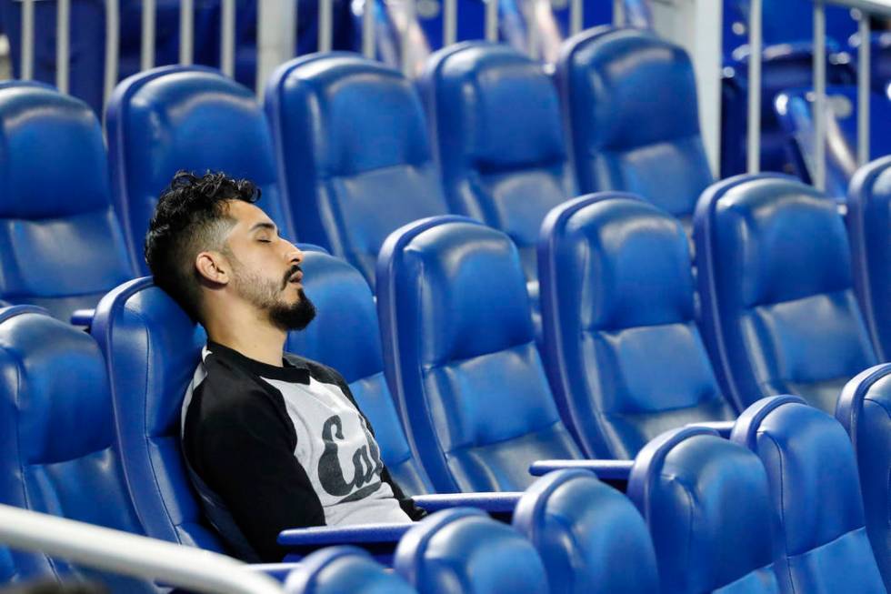 A spectator naps during the playing of the National Anthem before the start of a baseball game ...