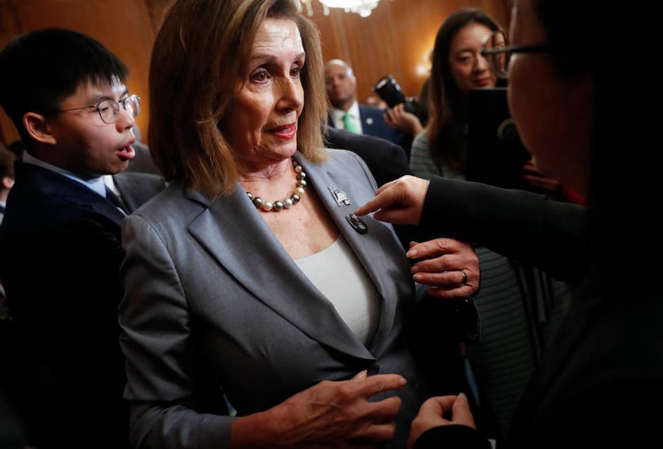 House Speaker Nancy Pelosi is given a lapel pin by a Hong Kong activist following a news confer ...