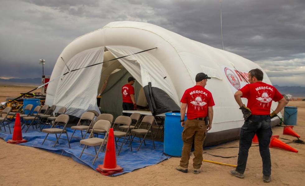 The medical crew looks to tamp down their tent while winds pick up as the start of the Aliensto ...