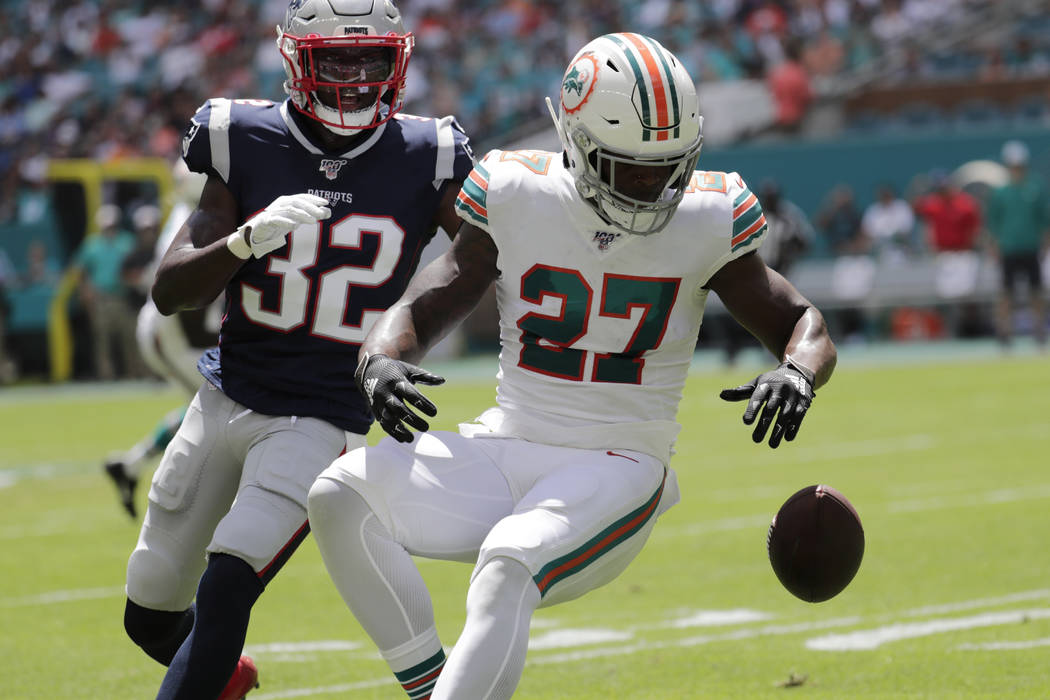 Miami Dolphins running back Kalen Ballage (27) drops a pass under pressure from New England Pat ...