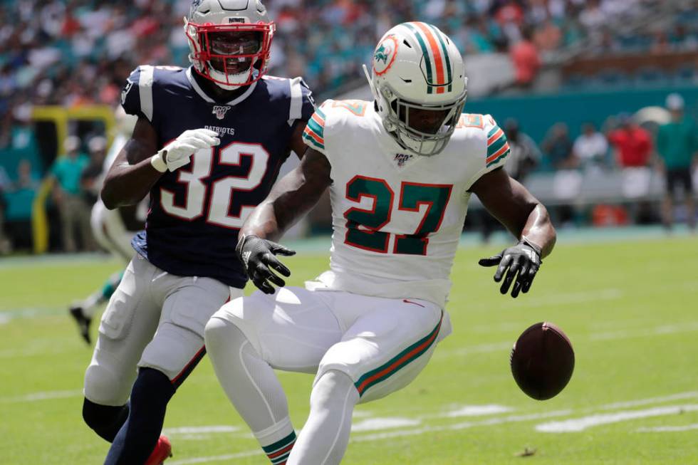 Miami Dolphins running back Kalen Ballage (27) drops a pass under pressure from New England Pat ...