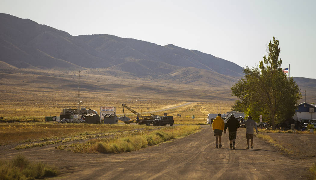 Attendees walk into the morning sun as the construction crew begins work on finishing the main ...