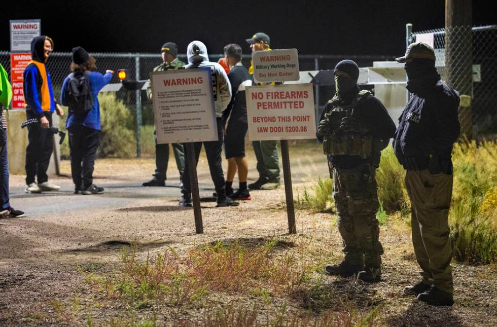 Security personnel and attendees stand along the fence line near the back gate of Area 51 in ho ...