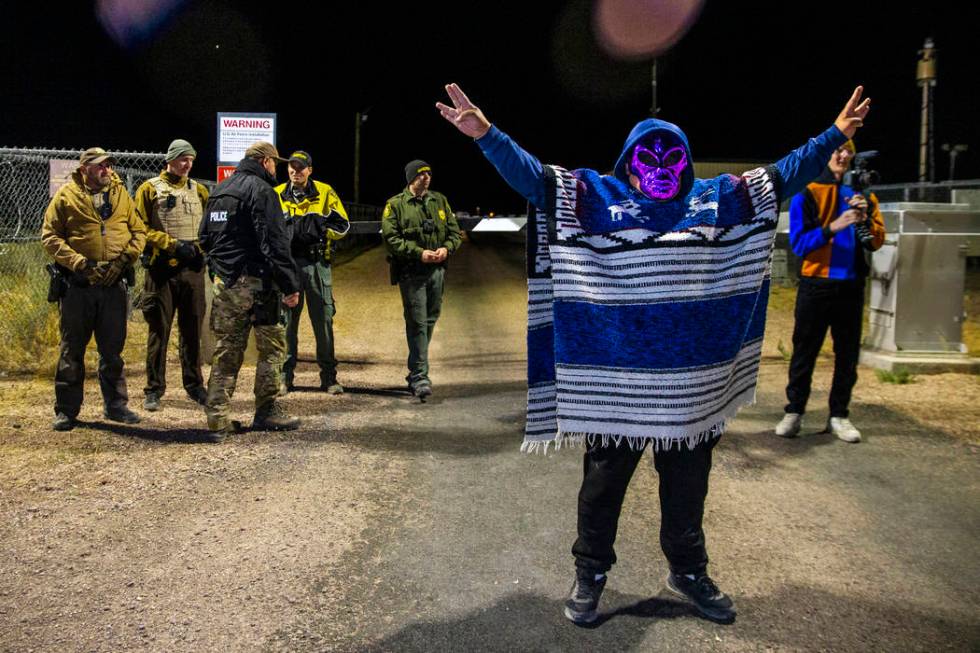 A costumed man stands near security personnel outside the back gate of Area 51 in homage to the ...