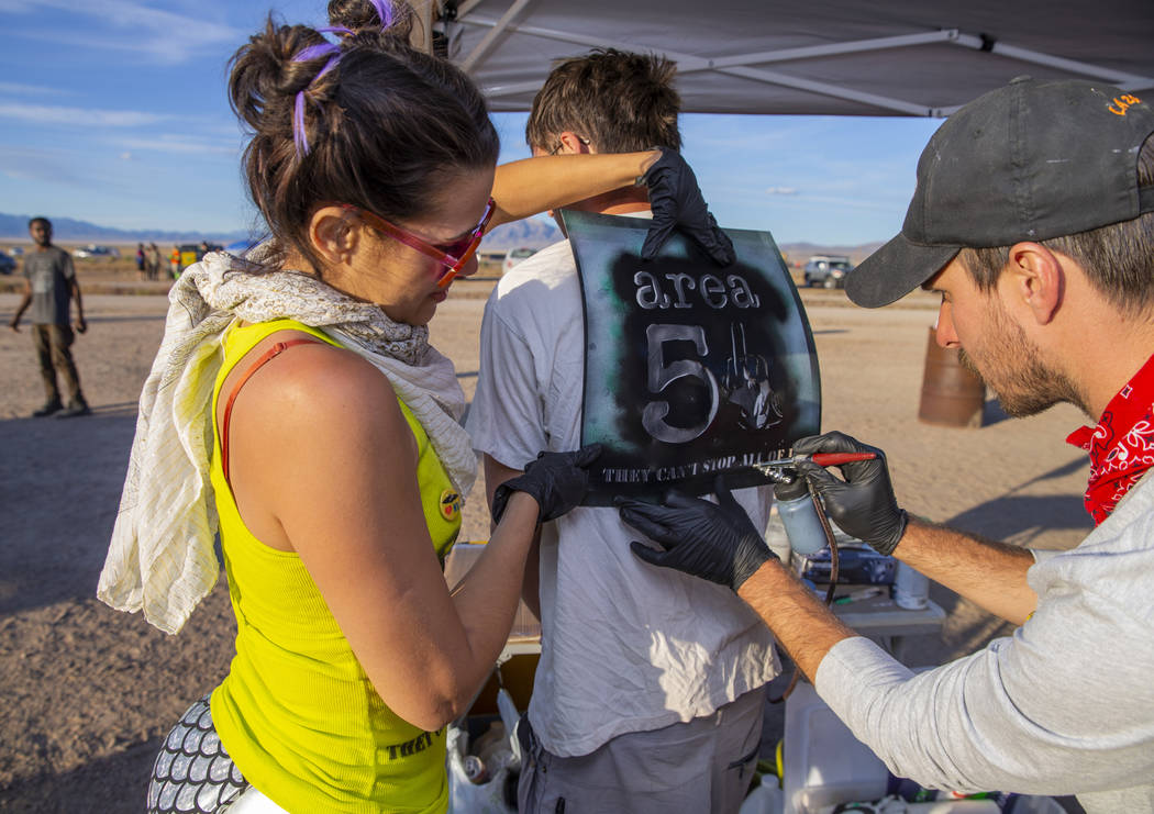 Robert Dobie, center, of Norway has his shirt stenciled by Marissol Martins, left, and Michael ...