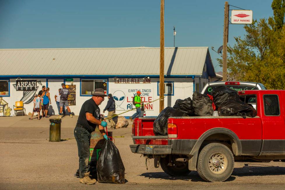 Kevin Dingo picks up bags of trash stacked in the parking area across from the Little A'Le'Inn ...