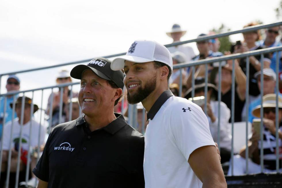 Phil Mickelson, left, and Stephen Curry pose for pictures before hitting from the first tee of ...