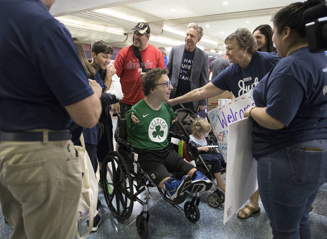 Michael Perrino, middle, 16, from Mashpee, Mass., is greeted by Miracle Flight employee Je ...