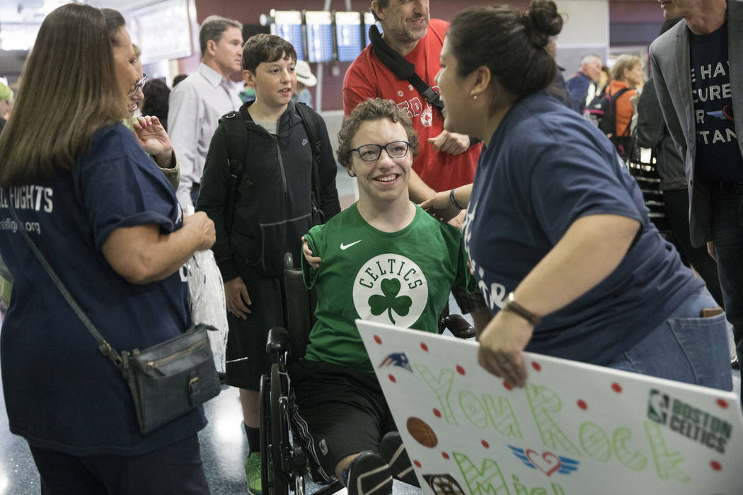 Michael Perrino, middle, 16, from Mashpee, Mass., is greeted by Miracle Flight employees i ...