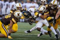 Wyoming defenders Cassh Maulia (46), Logan Wilson (30)and Mario Mora (97) tackle Missouri runni ...