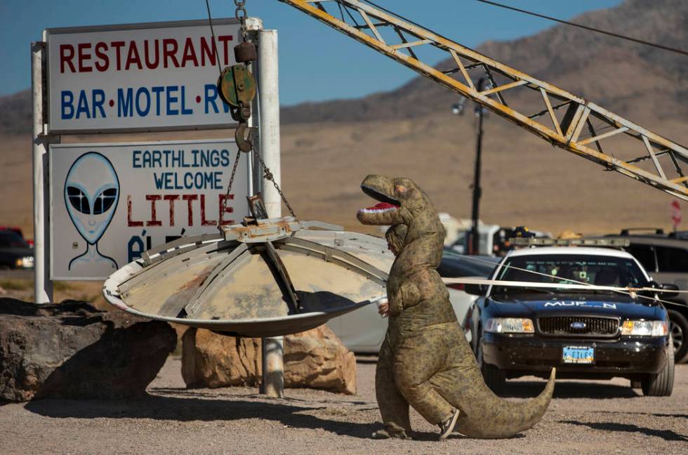 A T-Rex costumed festivalgoer walks over to the flying saucer outside the Little A'Le'Inn durin ...