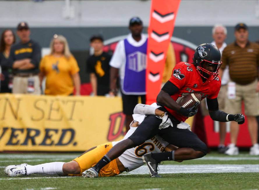 UNLV wide receiver Devonte Boyd (83) is tackled by Wyoming defensive back Marcus Epps (6) durin ...