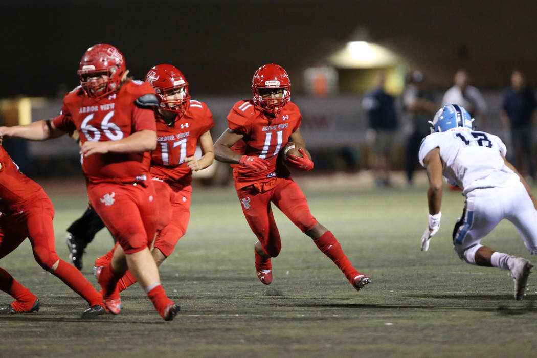 Arbor View's Jaedyn Jackson (11) runs the ball with Kyle Holmes (17) and Gavin Fleming (66) blo ...