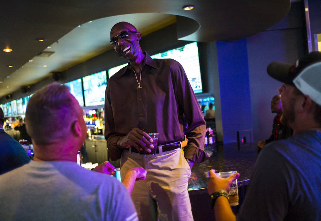 George Bell, who stands 7 feet 8 inches tall, talks with tourists while hanging out at the Long ...