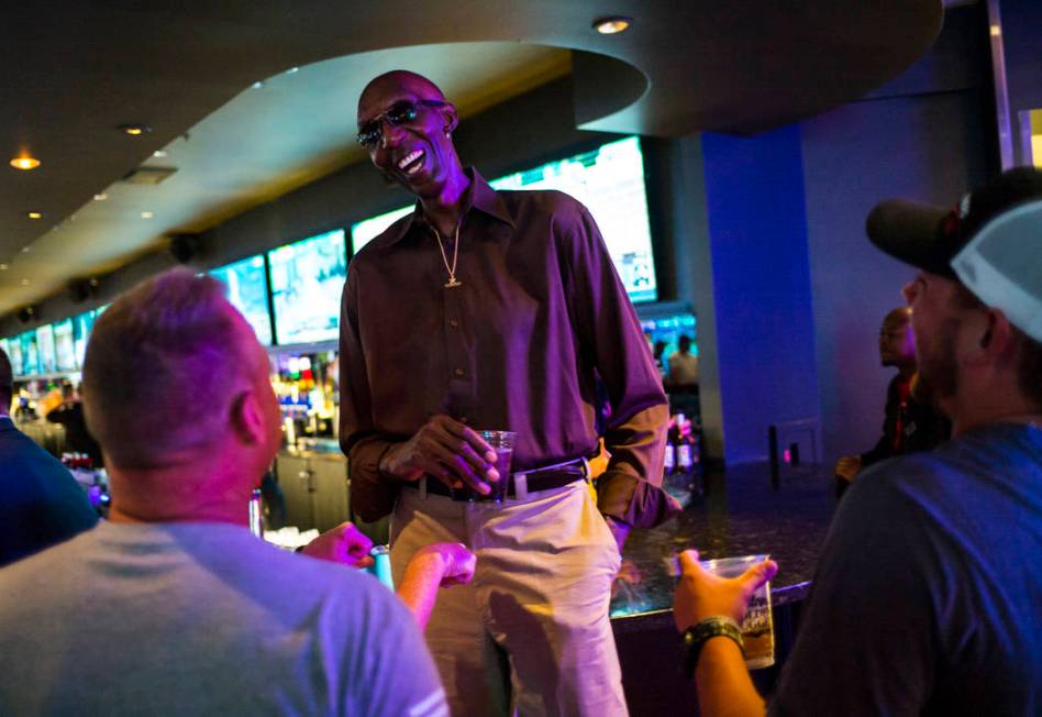 George Bell, who stands 7 feet 8 inches tall, talks with tourists while hanging out at the Long ...