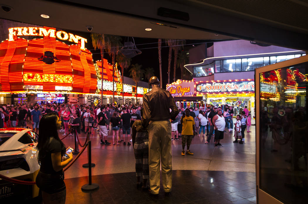 George Bell, who stands 7 feet 8 inches tall, poses for pictures on the Fremont Street Experien ...