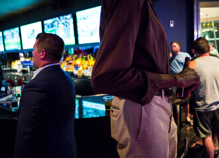 George Bell, who stands 7 feet 8 inches tall, holds a beer while hanging out at the Longbar at ...