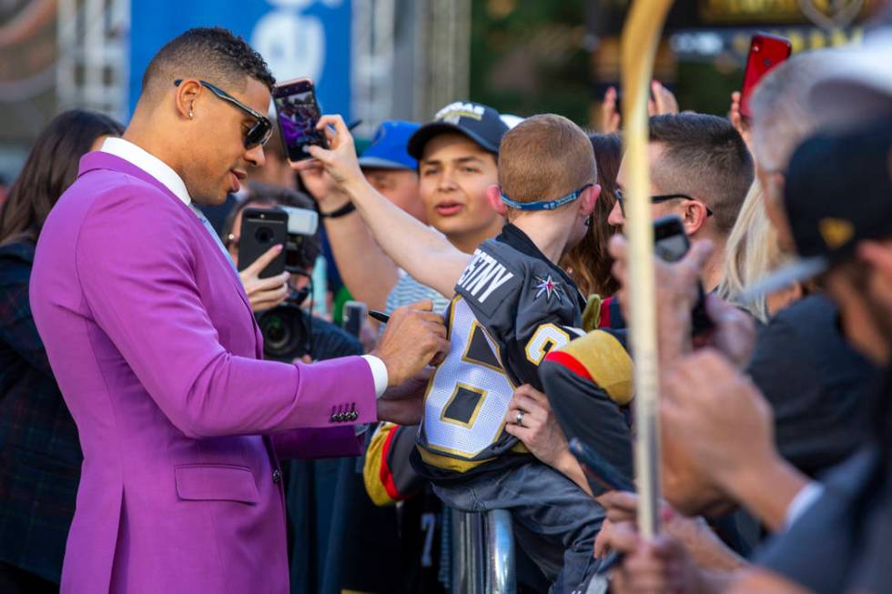 Vegas Golden Knights right wing Ryan Reaves signs an autograph for a fan while walking the gold ...