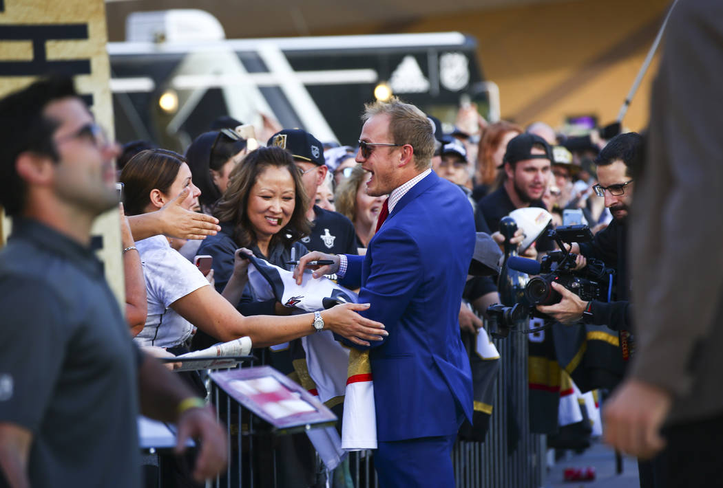 Golden Knights' Nate Schmidt signs autographs on the gold carpet after arriving for the NHL sea ...