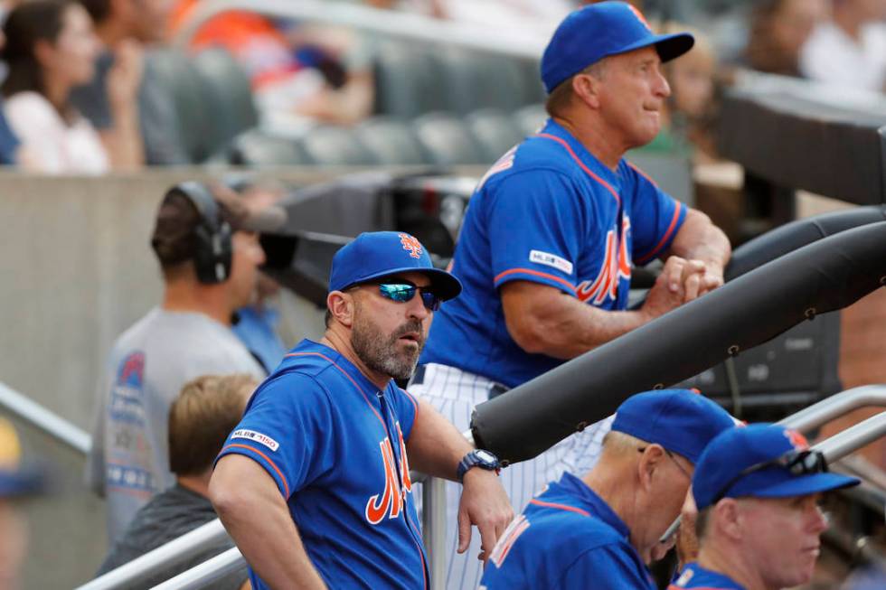 New York Mets manager Mickey Callaway, front left, looks from the dugout during a baseball game ...