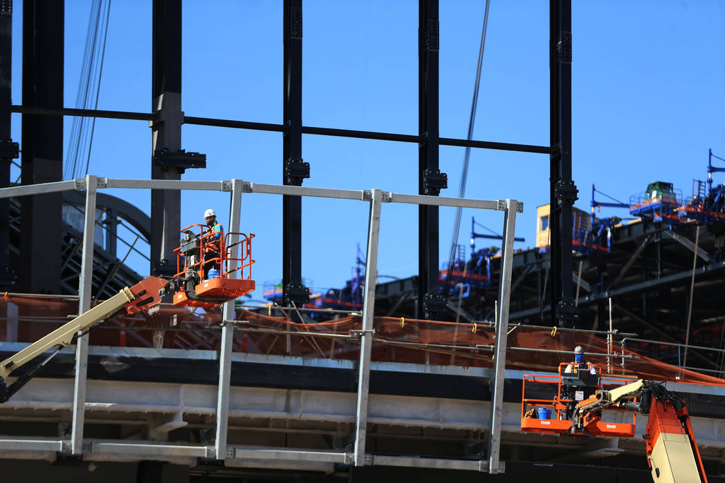 Workers stand on lifts at the Raiders Allegiant Stadium construction site in Las Vegas, Thursda ...