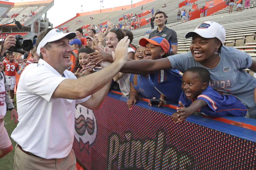 Florida head coach Dan Mullen high fives fans as he leaves the field after defeating Towson in ...
