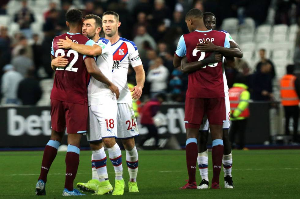 Crystal Palace midfielder James McArthur (18) embraces West Ham United forward Sebastien Haller ...