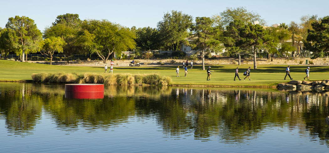 Golfers make their way up the fairway at hole 16 past a water feature during the third round of ...