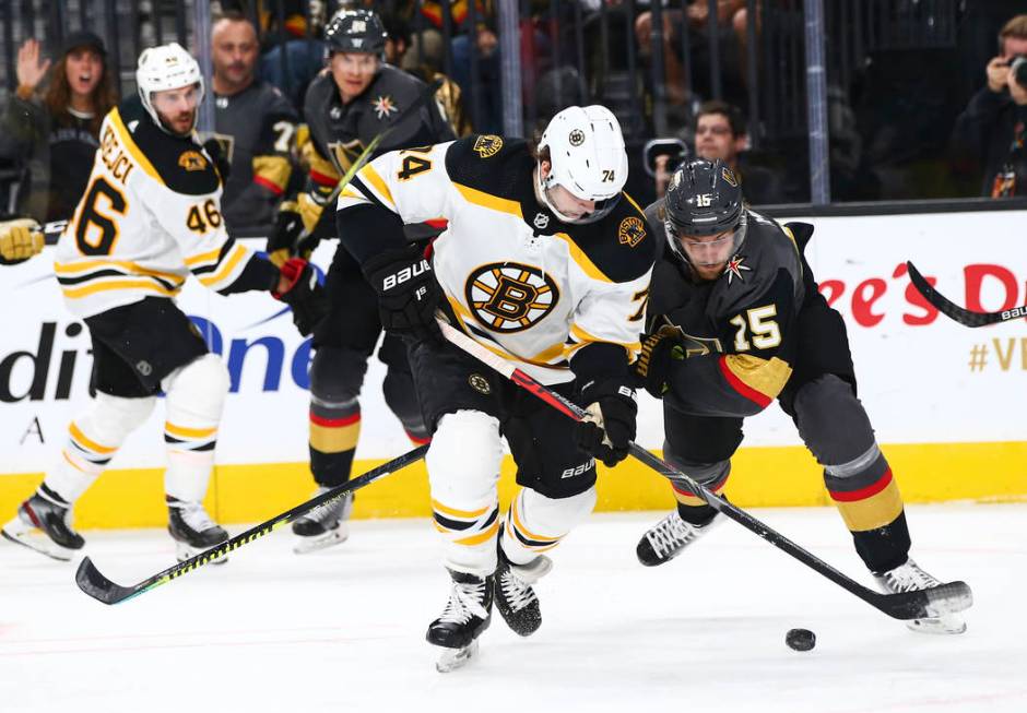 Boston Bruins' Jake DeBrusk (74) and Golden Knights' Jon Merrill (15) battle for the puck durin ...